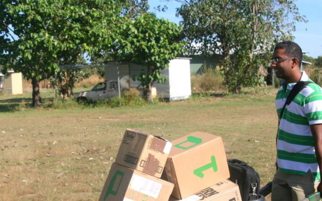 man pushing wheel barrow with boxes stacked on it