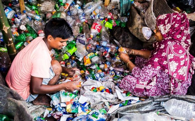 two people sifting through pile of plastic bottles 