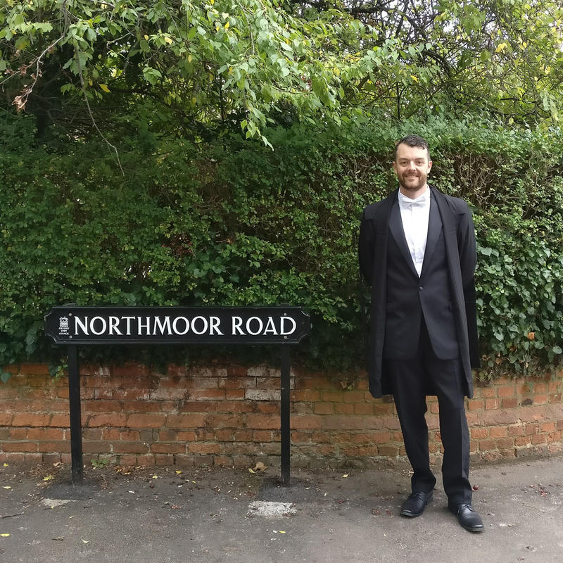 Kevin standing by the road sign for Northmoor Road in Oxford in full Oxford attire